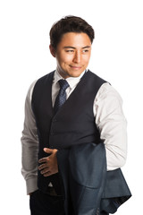 Confident and attractive businessman standing against a white background looking away, wearing a shirt, tie and vest with his jacket on his arm.