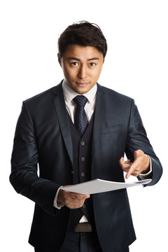 Handsome businessman in a blue suit and tie, standing against a white background with a document in his hand with a very displeased look on his face, feeling angry and unsatisfied.