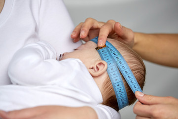 close up of hands with tape measuring baby head
