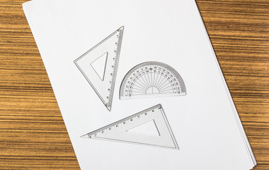 Set of triangle and half circle protractor on white paper,top view shot.