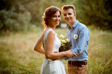 Couple on the nature, the bride and groom hugging at the wedding.