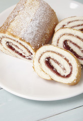 A strawberry jam Swiss roll cake on a blue wooden table top background