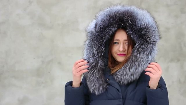 Closeup beautiful smiling girl wearing blue coat with fur hood in winter, snow