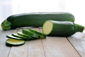 Some courgette sliced on a white wooden table in a rusic kitchen. Empty copy space for editor's text.