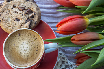 Obraz na płótnie Canvas One cup of coffee with chocolate biscuit and red tulips