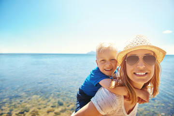 Woman holding son on back on seaside