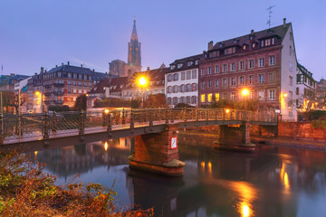 Picturesque landscape with bridge and river embankment Ile during morning blue hour, Strasbourg Cathedral in the background, Strasbourg, Alsace, France