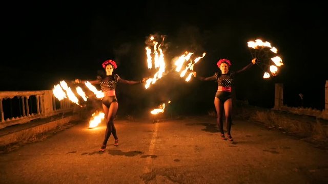 Two beautiful girls in costumes dancing with fire