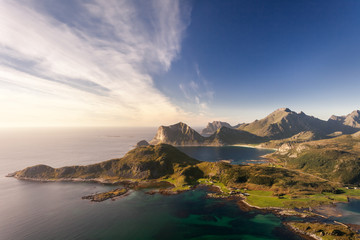 Amazing scenery of sunset over bay between mountains on Lofoten Islands, Norway, Scandinavia. Romantic mood watching midnight sun laying its beams on ocean and peaks rising out of the sea. 