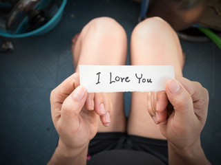 Woman's hand holding a paper with the message I received from her lover on Valentine's Day.