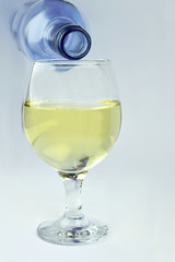 Bottle of white wine glass being poured in a glass isolated