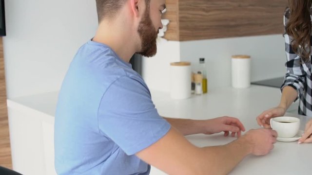 Young smiling couple dinking coffee together in the kitchen and talking 