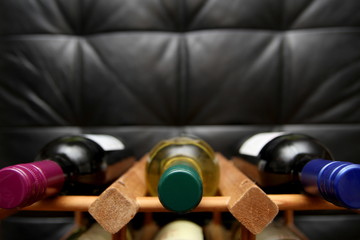 Closeup of bottles in a wooden wine rack on dark background