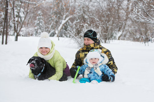 family mother, father and little daughter with a dog on winter walk