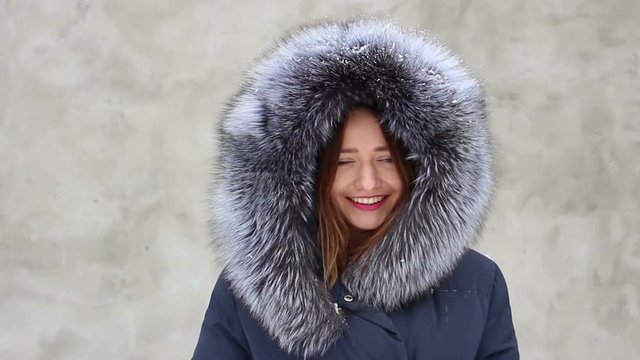 Closeup beautiful smiling girl wearing blue coat with fur hood in winter, snow