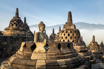 Buddha statue with mist and mountain at Borobudur temple, Indonesia