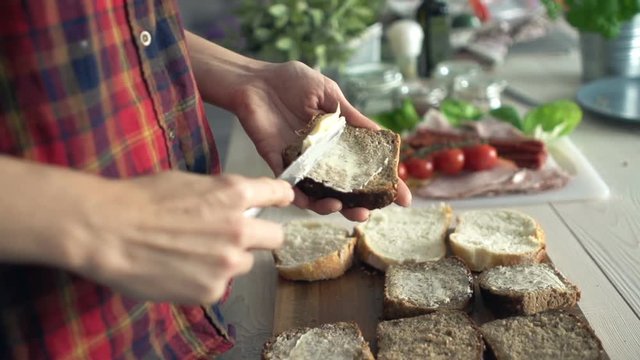 Woman spreading butter on bread in kitchen
