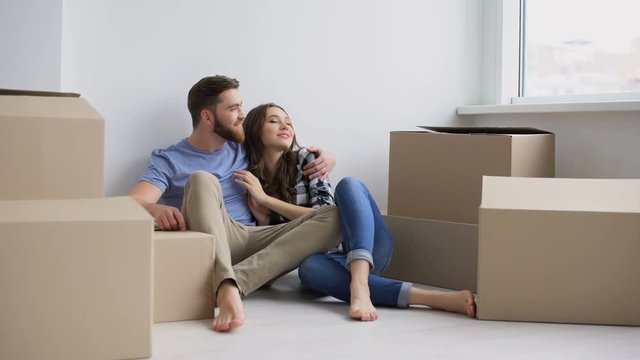 Young happy couple sitting on the floor of their new appartment and planning redecoration
