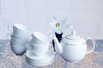 White porcelain tea set - stacked cups and saucers and tea pot.