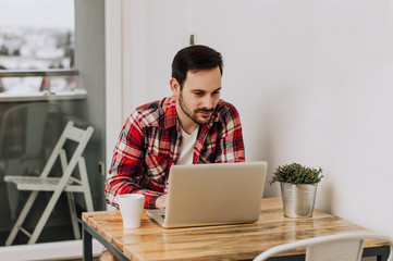 Serious handsome bearded man sitting on workplace and working wi