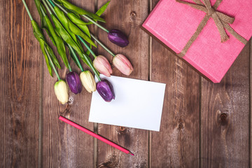 Romantic and pink Valentine's day decoration with present and DIY love card. Beautiful bouquet of purple tulips and card on wooden background. Mothers day card .On March 8 is Women's Day