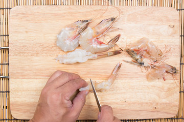 Chef cooking raw shrimp with knife