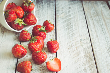 Ripe Strawberries in cup on wooden table background. Copy space
