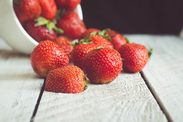 Ripe Strawberries in cup on wooden table background. Copy space