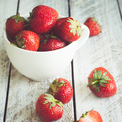 Ripe Strawberries in cup on wooden table background. Copy space
