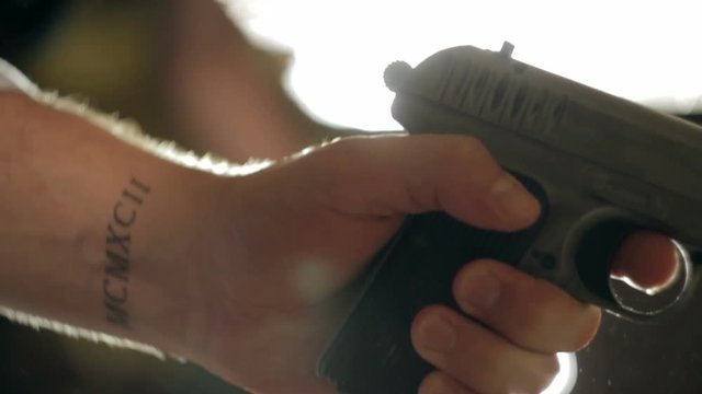 Man cocks the gun. Close-up of hand