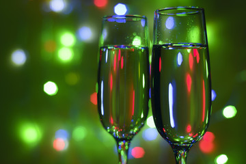 Glasses of champagne on a green background with a garland