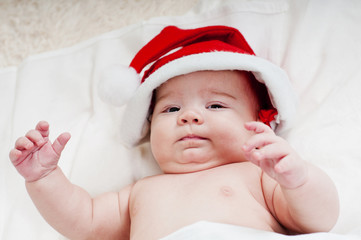 Charming newborn baby dressed as Santa Claus on the bed