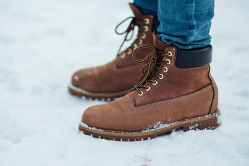 Men's warm winter boots on snow. Brown men's winter boots closeup