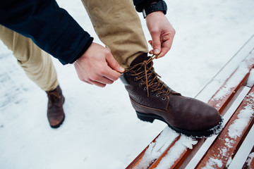 Shoelaces of boots. Man tying shoelaces on winter boots in winter day - obrazy, fototapety, plakaty