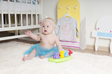 Baby girl playing on the carpet at home or kindergarten