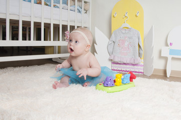 Baby girl playing on the carpet at home or kindergarten