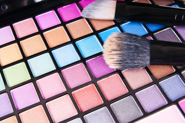 make-up brushes on colorful eye shadows palette