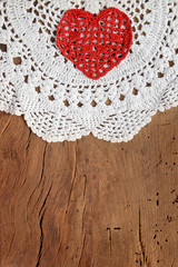 Valentine's day background with red knitted heart on white hand crochet cup and table pad rustic