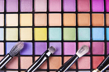 make-up brushes on colorful eye shadows palette