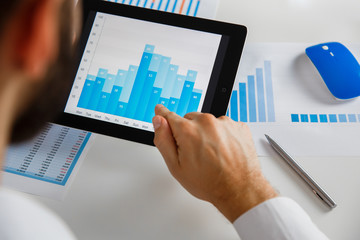 Business person analyzing financial statistics displayed on the tablet screen