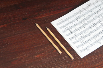Music notes and two pencils on table