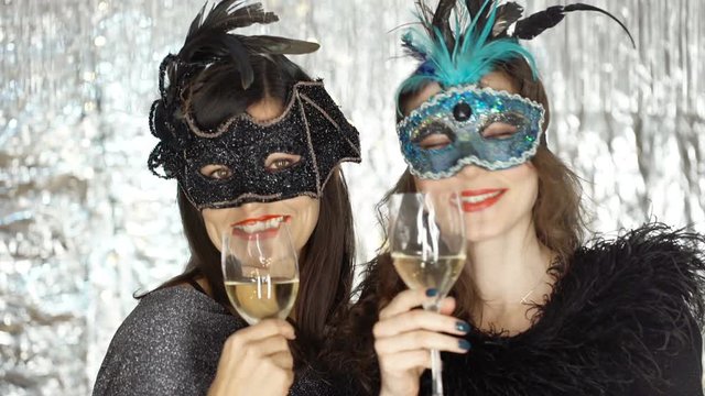 Women drinking champagne and smiling to the camera at the masquerade party, steadycam shot
