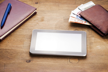 money, tablet and notebooke on table