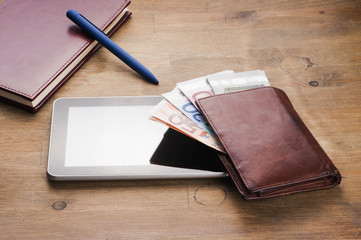 money, tablet and notebooke on table