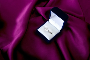 Engagement ring on the violet satin. Selective focus and small depth of field.