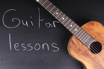 Old guitar on the chalkboard and the inscription 
