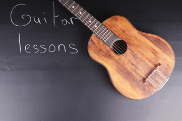 Fototapeta premium Old guitar on the chalkboard and the inscription 