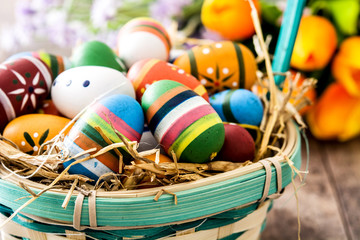 Colored easter eggs in a basket on wooden table
