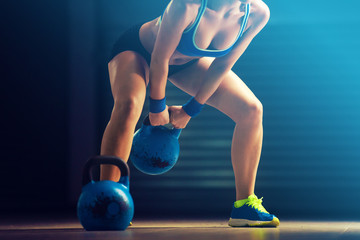Young fit woman training by kettlebell.