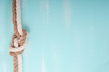 Marine rope with a knot on a wooden background turquoise